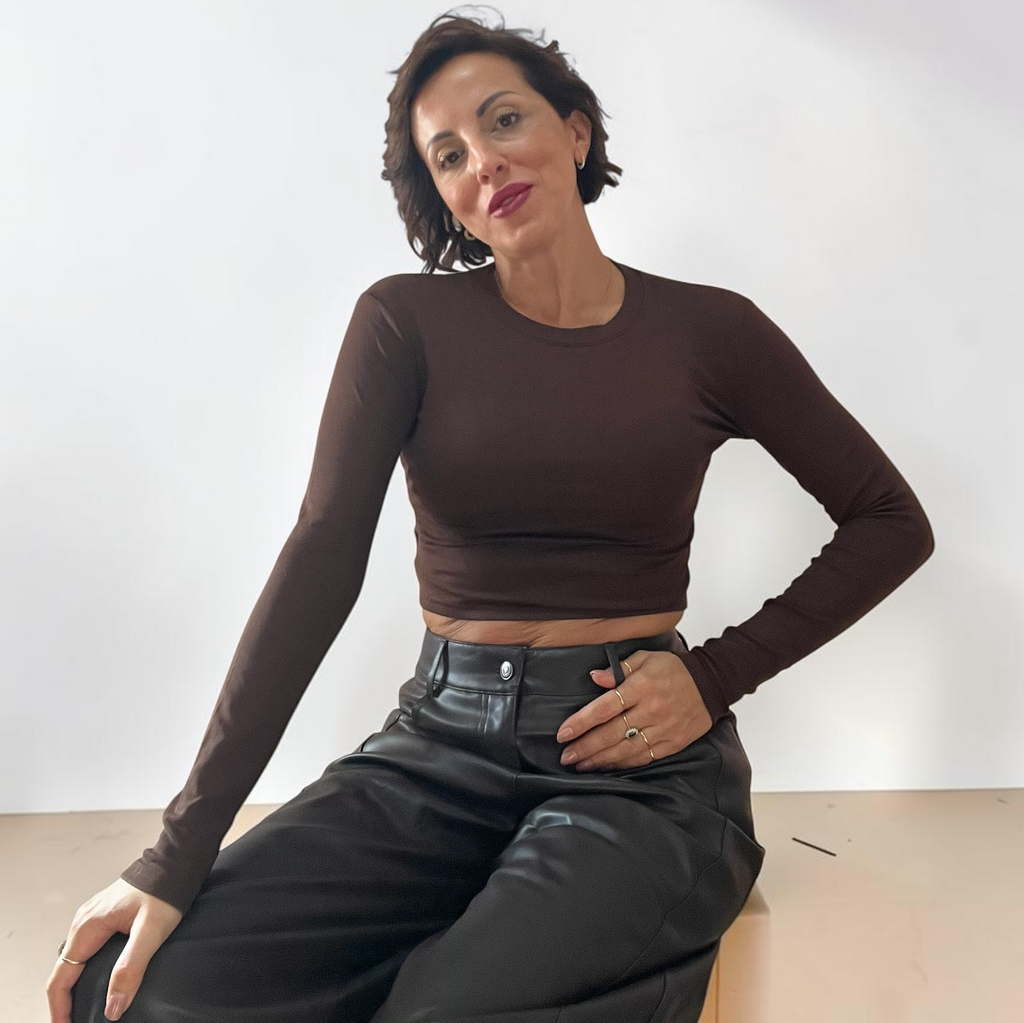Modella indossa una maglia crop a maniche lunghe marrone Caldea Boutique con girocollo, abbinata a pantaloni in pelle