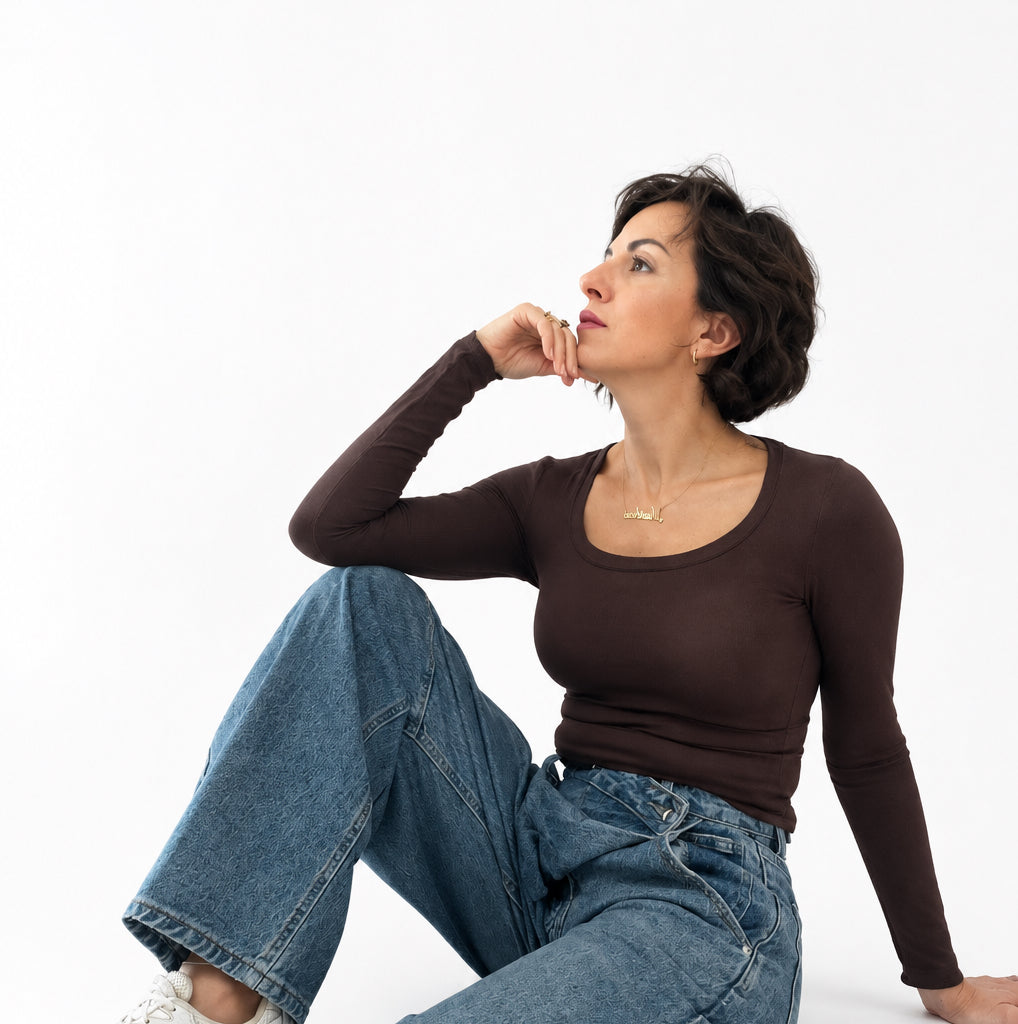 Modella indossa maglia a maniche lunghe Caldea Boutique color testa di moro aderente con jeans e sneakers
