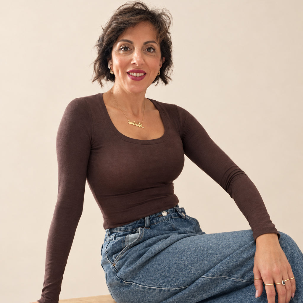 Modella indossa una maglia a maniche lunghe Caldea Boutique color testa di moro con scollo rotondo e jeans ampi
